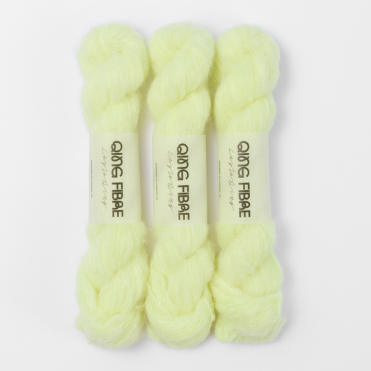 Three labelled hanks of Lightning Melted Baby Suri 25g yarn in pale neon yellow.