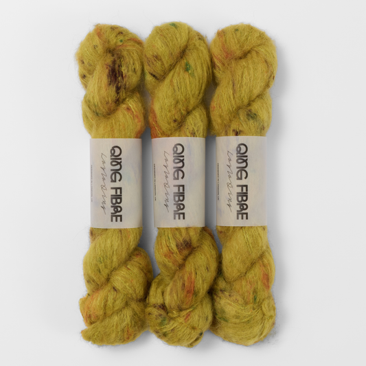 Three labelled hanks of Guardian Melted Baby Suri 25g yarn in mustard yellow with brown and green markings.