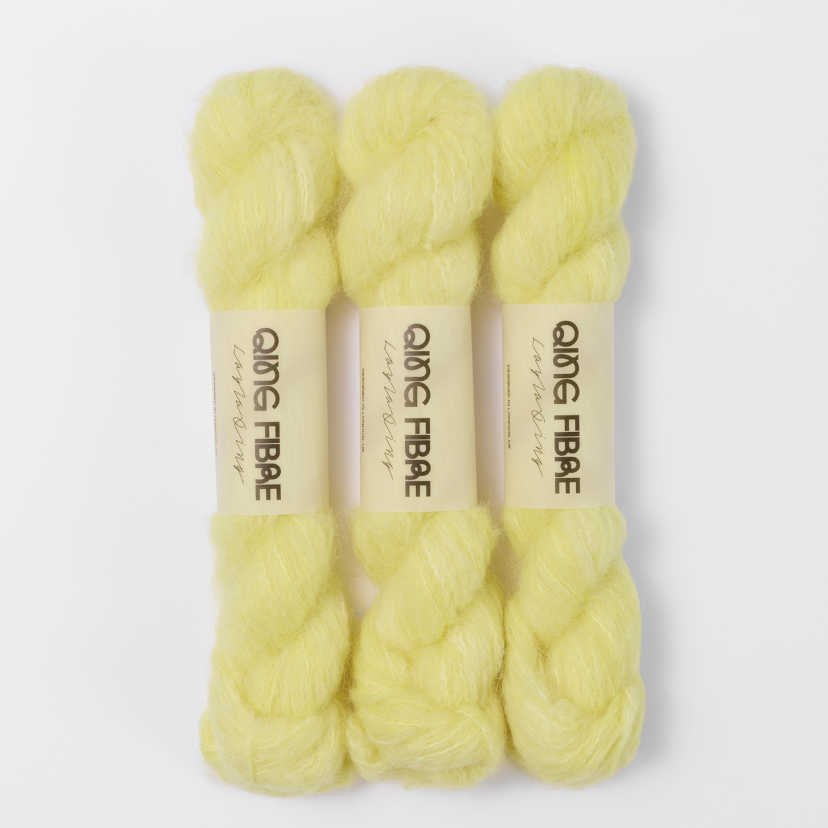 Three labelled hanks of Cocoon Melted Baby Suri 25g yarn in pale yellow.