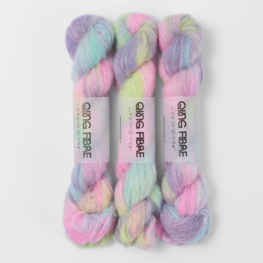 Three labelled hanks of Cloud Melted Baby Suri 25g yarn in pastel pink, yellow, blue and lilac.
