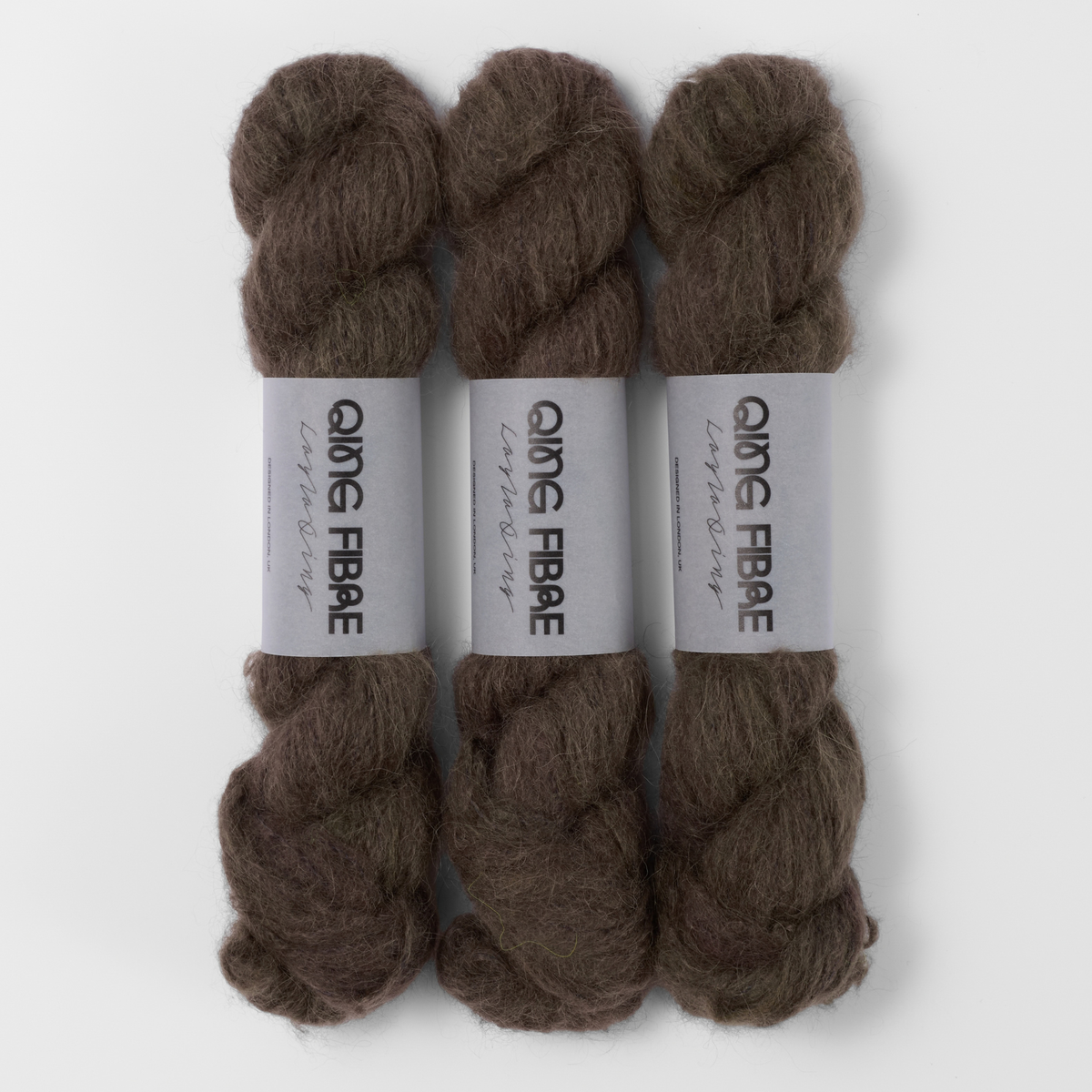 Three labelled hanks of Soot Melted Baby Suri 25g yarn in dark charcoal.