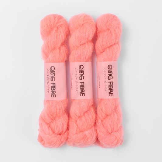 Three labelled hanks of Shrimp Melted Baby Suri 25g yarn in coral orange.