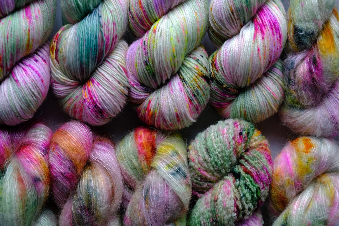 Colorful hand-dyed yarn skeins in pink, green, orange, and yellow shades, close-up