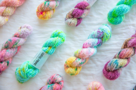 Colorful hand-dyed skeins of yarn arranged on a white textured background