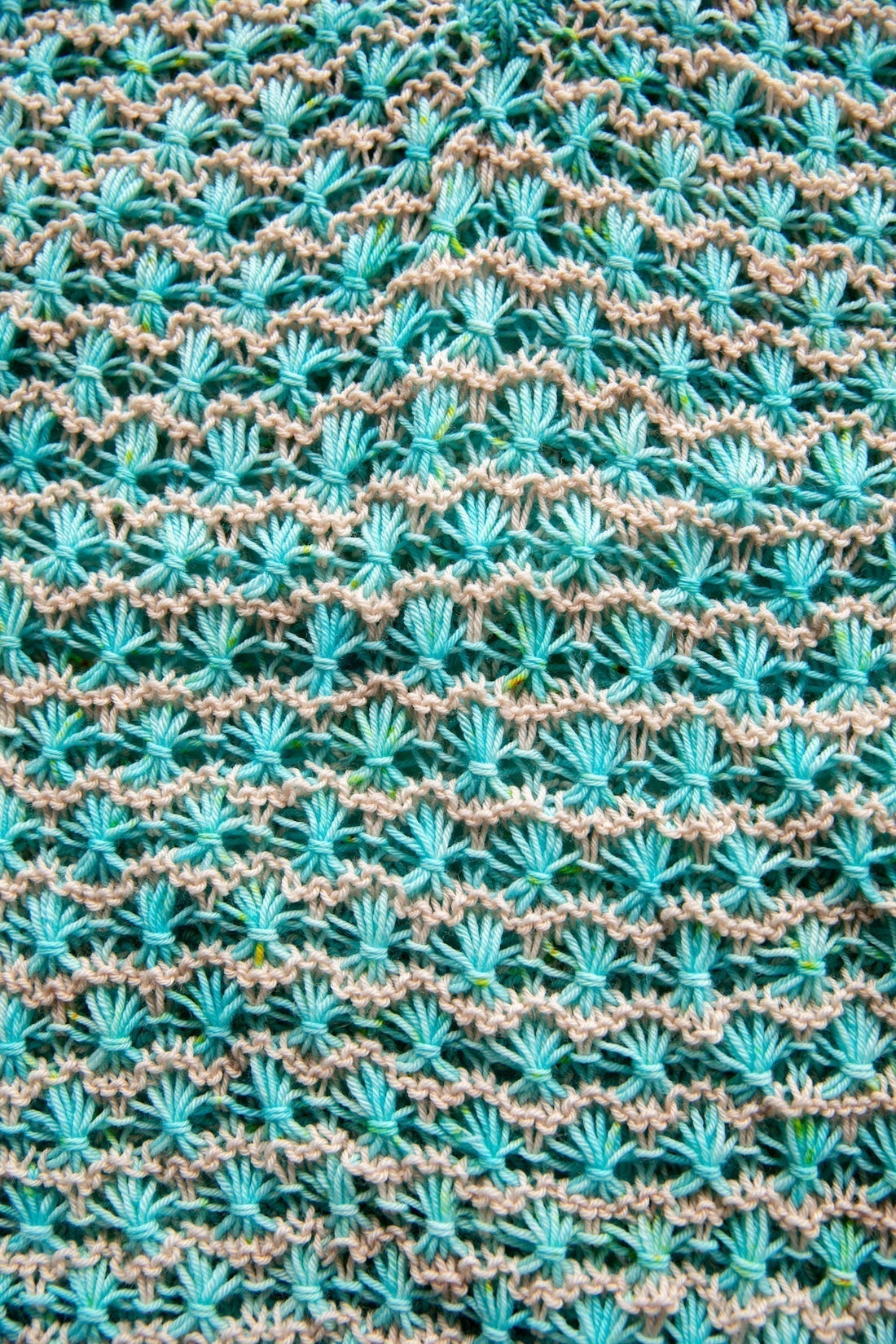 Turquoise and beige textured knit pattern with shell stitches, close-up yarn detail