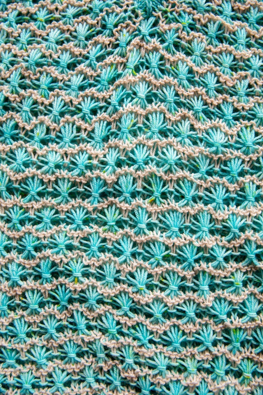 Turquoise and beige textured knit pattern with shell stitches, close-up yarn detail