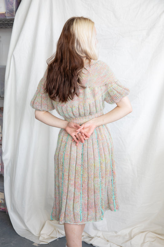 Back view of woman with long two-toned hair wearing a pastel knit dress indoors