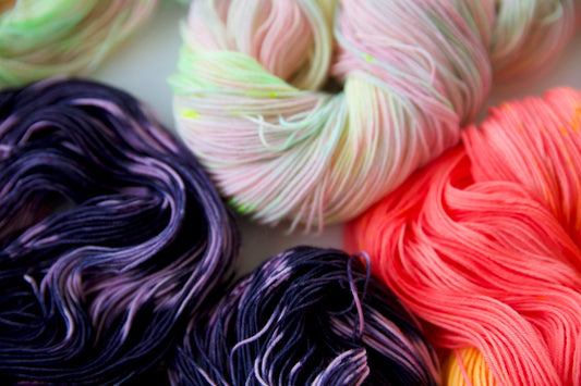 Closeup of colorful yarn skeins in purple, pink, peach, and pastel shades