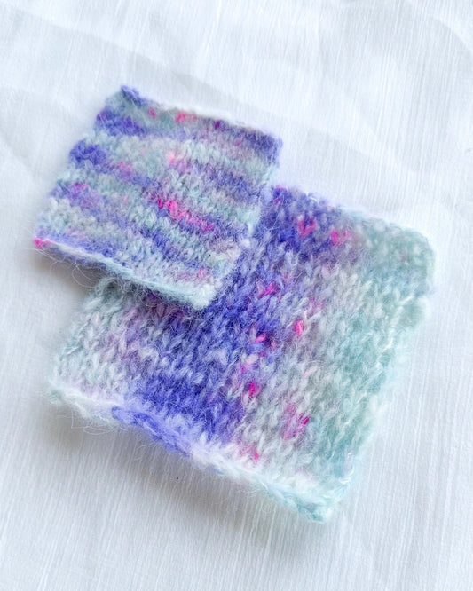 Two pastel multicolored knitted swatches on white fabric background