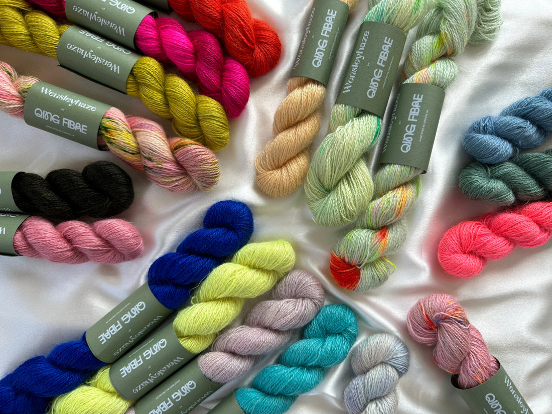 Colorful QING FIBRE Wensleydale yarn skeins on white satin background