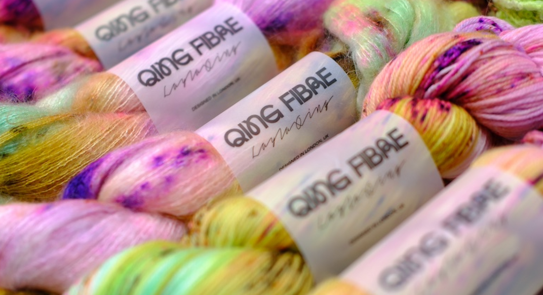 Colorful Qing Fibre yarn skeins with speckled pastel shades and branded labels
