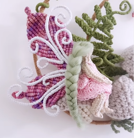 Handmade macrame butterfly with pink and purple wings and green leaves detail