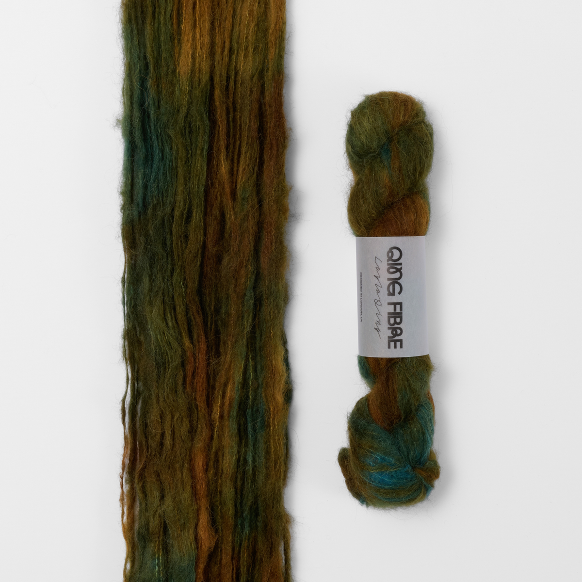 Nyx Melted Baby Suri 25g: dark green and brown yarn, shown loose beside a labelled hank.