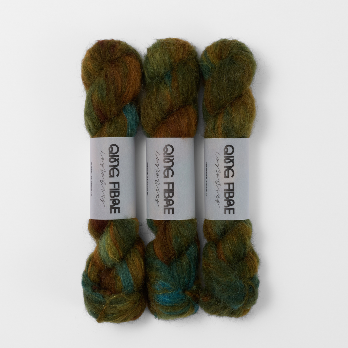 Three labelled hanks of Nyx Melted Baby Suri 25g yarn in dark green and brown.