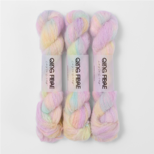 Three labelled hanks of Mother of Pearl Melted Baby Suri 25g yarn in pastel pink, lilac and yellow.