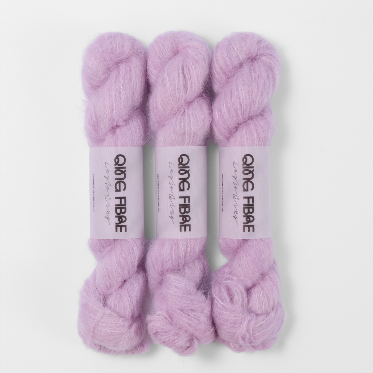Three labelled hanks of Thistle Melted Baby Suri 25g yarn in pale lilac.