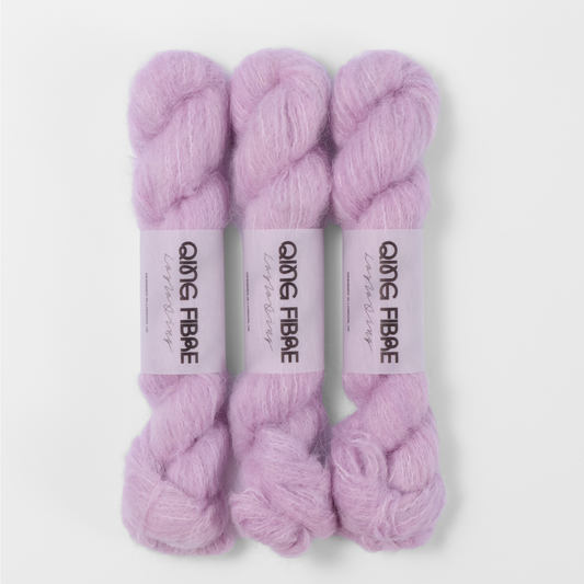 Three labelled hanks of Thistle Melted Baby Suri 25g yarn in pale lilac.