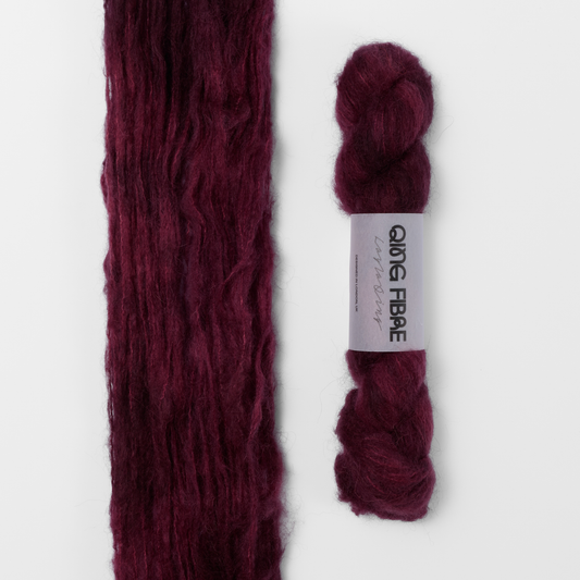 Hush Melted Baby Suri 25g: burgundy red yarn, shown loose beside a labelled hank.