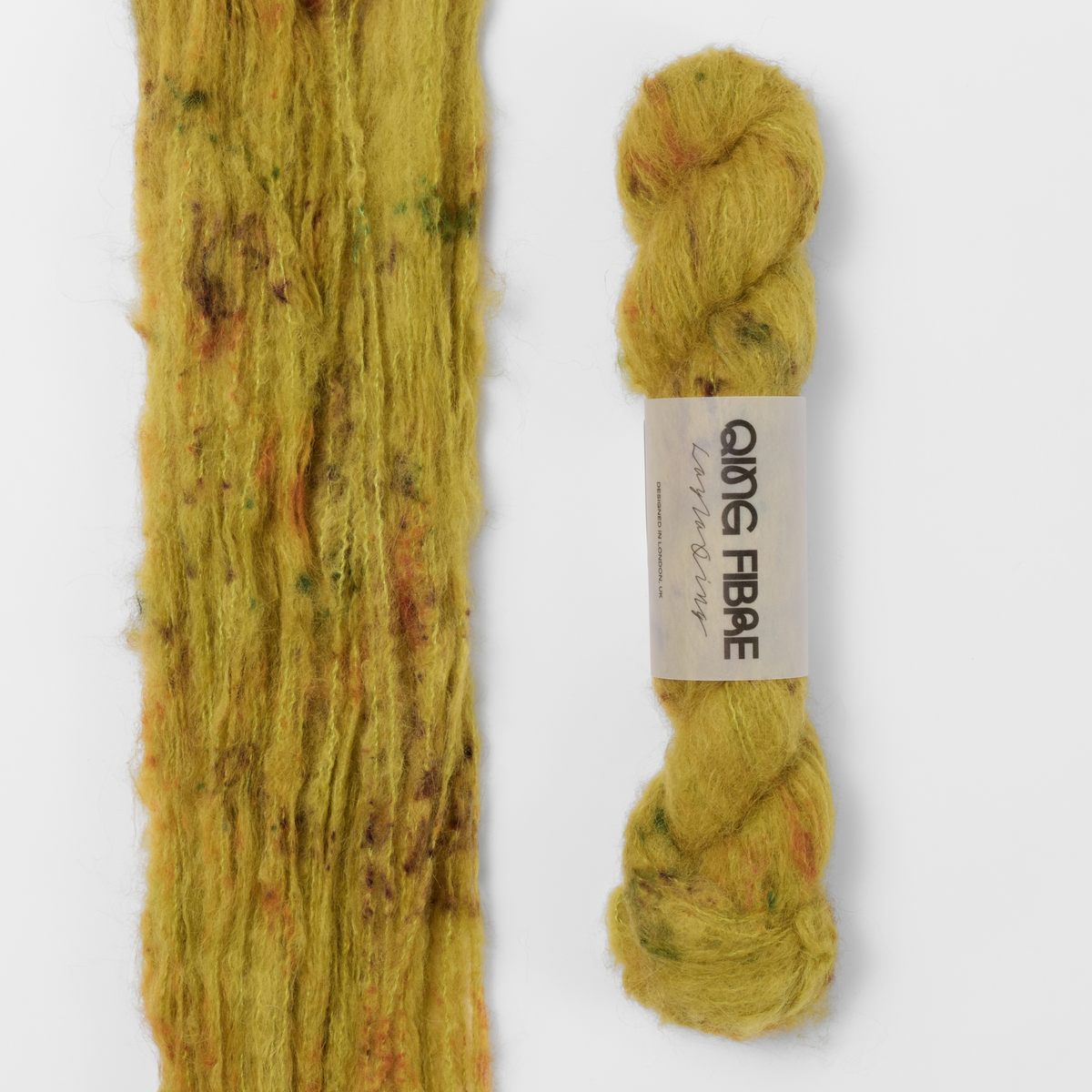 Guardian Melted Baby Suri 25g: mustard yellow with brown and green markings yarn, shown loose beside a labelled hank.