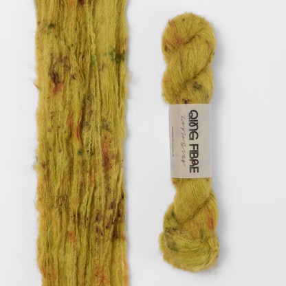 Guardian Melted Baby Suri 25g: mustard yellow with brown and green markings yarn, shown loose beside a labelled hank.