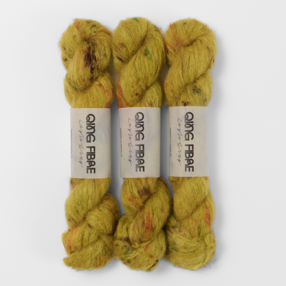 Three labelled hanks of Guardian Melted Baby Suri 25g yarn in mustard yellow with brown and green markings.