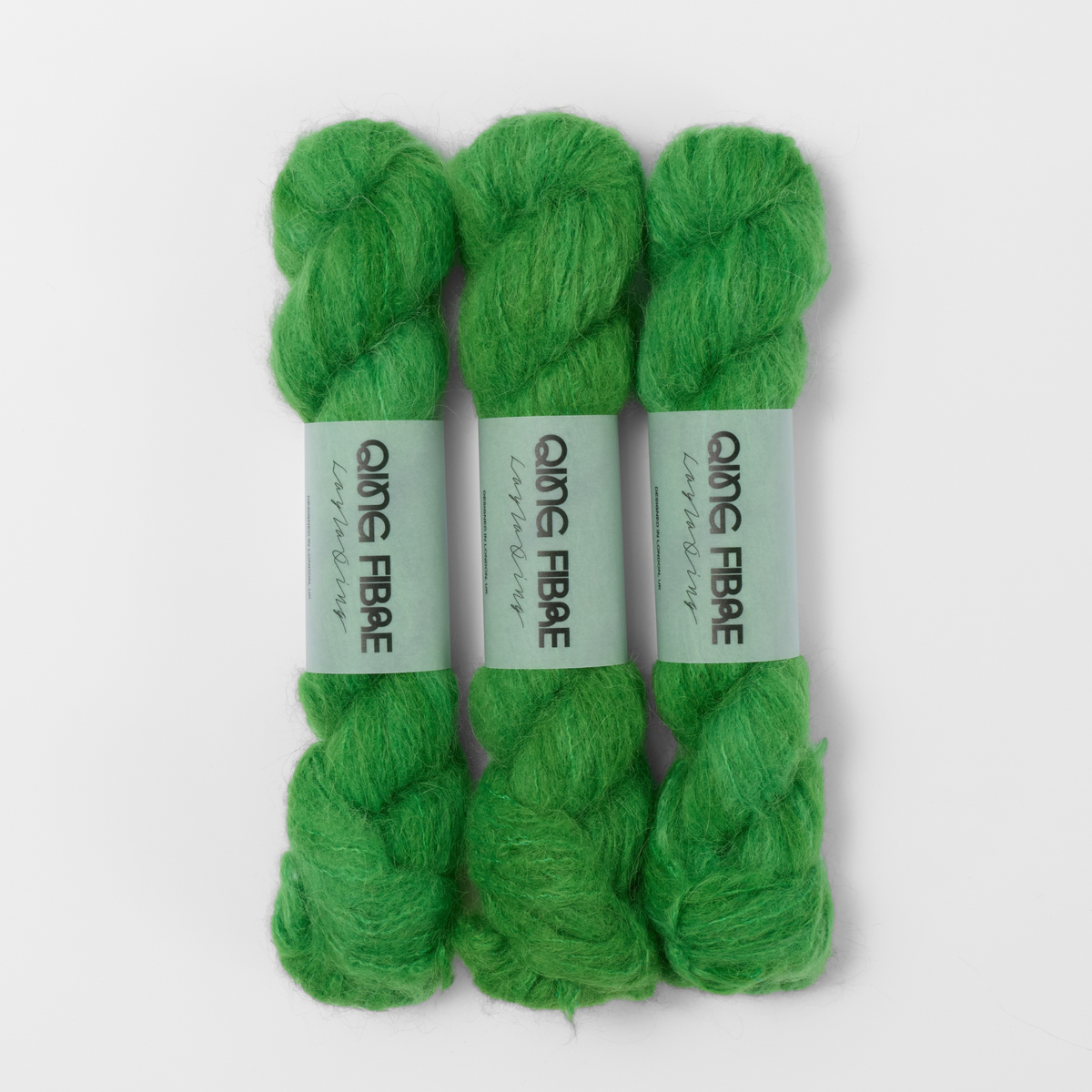 Three labelled hanks of Grass Melted Baby Suri 25g yarn in bright green.