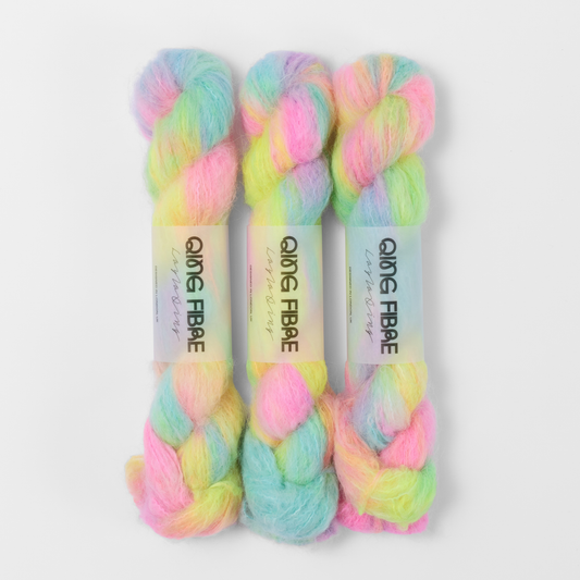Three labelled hanks of Flying Saucer Melted Baby Suri 25g yarn in bright pink, yellow and turquoise green.