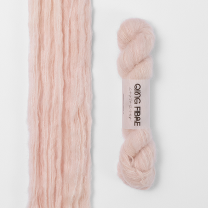 Dust Melted Baby Suri 25g: pale blush pink yarn, shown loose beside a labelled hank.