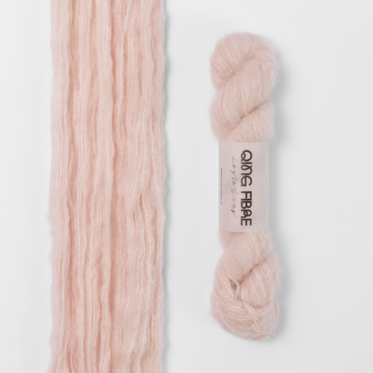 Dust Melted Baby Suri 25g: pale blush pink yarn, shown loose beside a labelled hank.