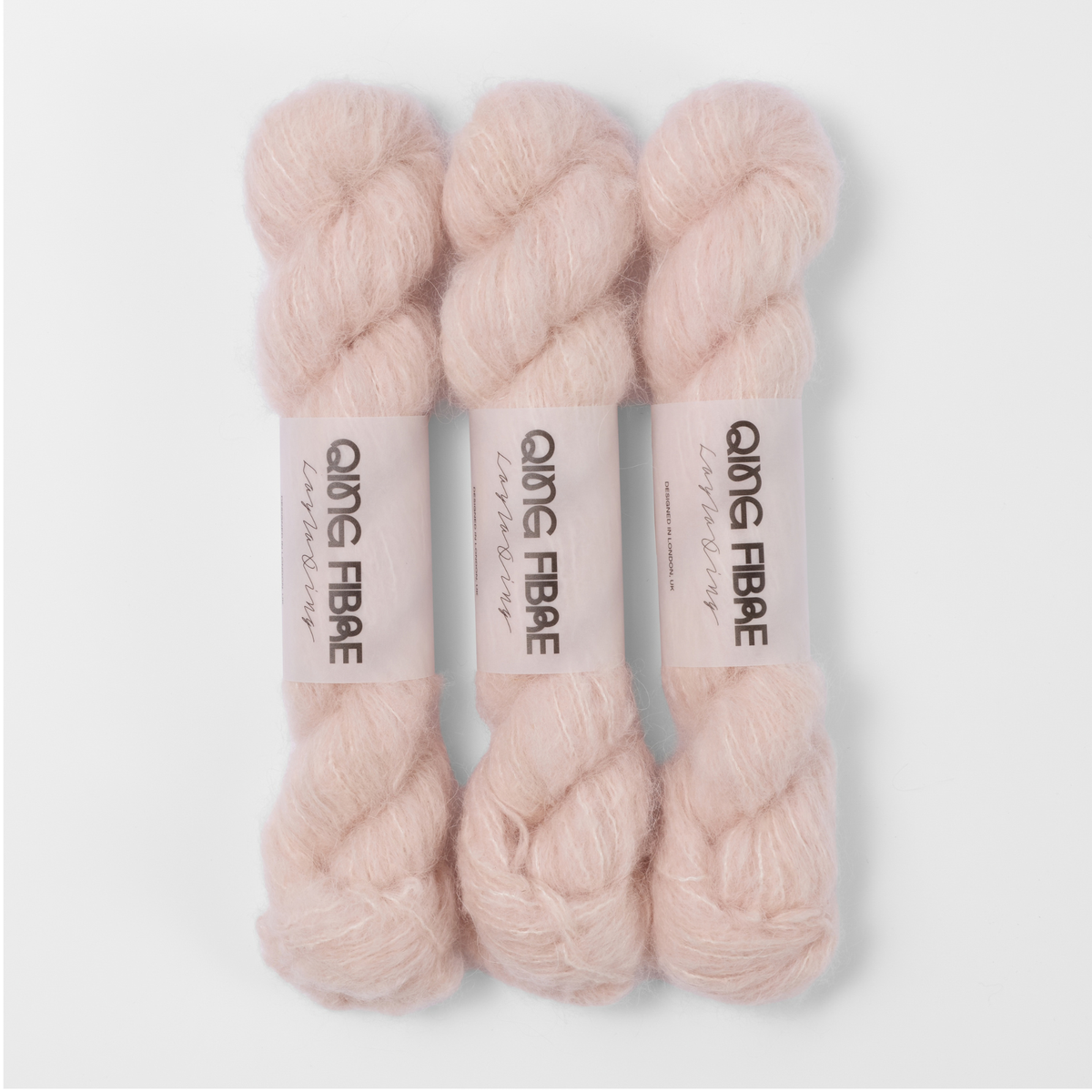 Three labelled hanks of Dust Melted Baby Suri 25g yarn in pale blush pink.