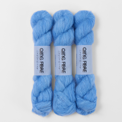 Three labelled hanks of Drift Melted Baby Suri 25g yarn in pale blue.