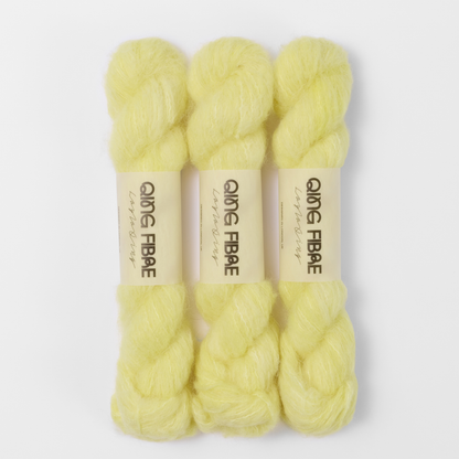 Three labelled hanks of Cocoon Melted Baby Suri 25g yarn in pale yellow.