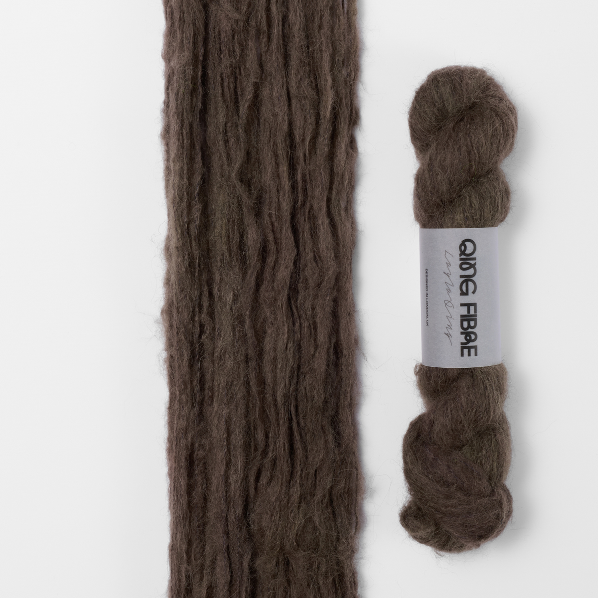 Soot Melted Baby Suri 25g: dark charcoal yarn, shown loose beside a labelled hank.