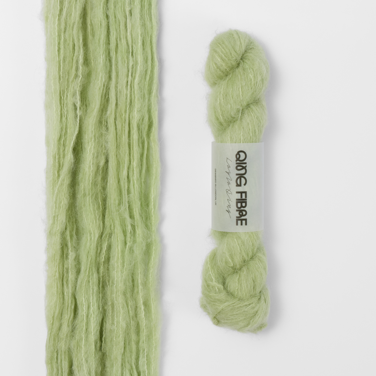 Cicada Melted Baby Suri 25g: pale sage green yarn, shown loose beside a labelled hank.