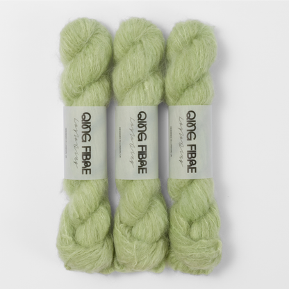 Three labelled hanks of Cicada Melted Baby Suri 25g yarn in pale sage green.
