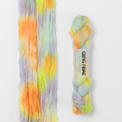 600 Volts Melted Baby Suri 25g: yellow and orange with green and lilac yarn, shown loose beside a labelled hank.