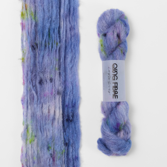 Moon Goddess Melted Baby Suri 25g: lavender with pink and green accents yarn, shown loose beside a labelled hank.