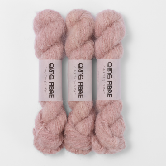 Three labelled hanks of Soft Clay Melted Baby Suri 25g yarn in dusty pink.