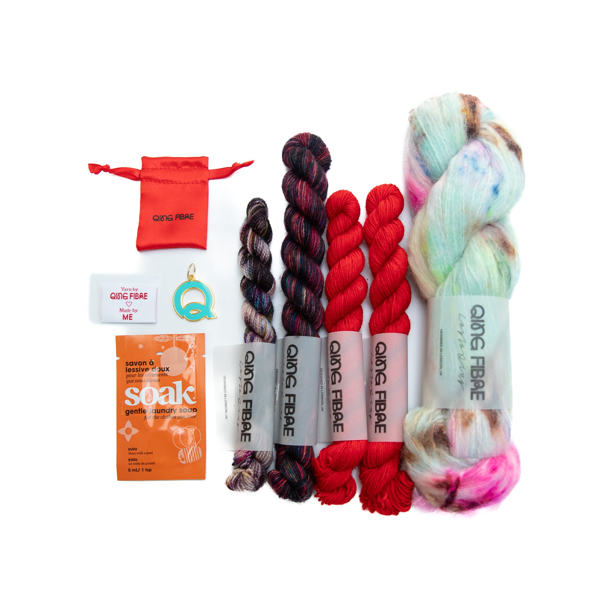 Collection of QING FIBRE hand dyed  yarn and accessories on a white background
