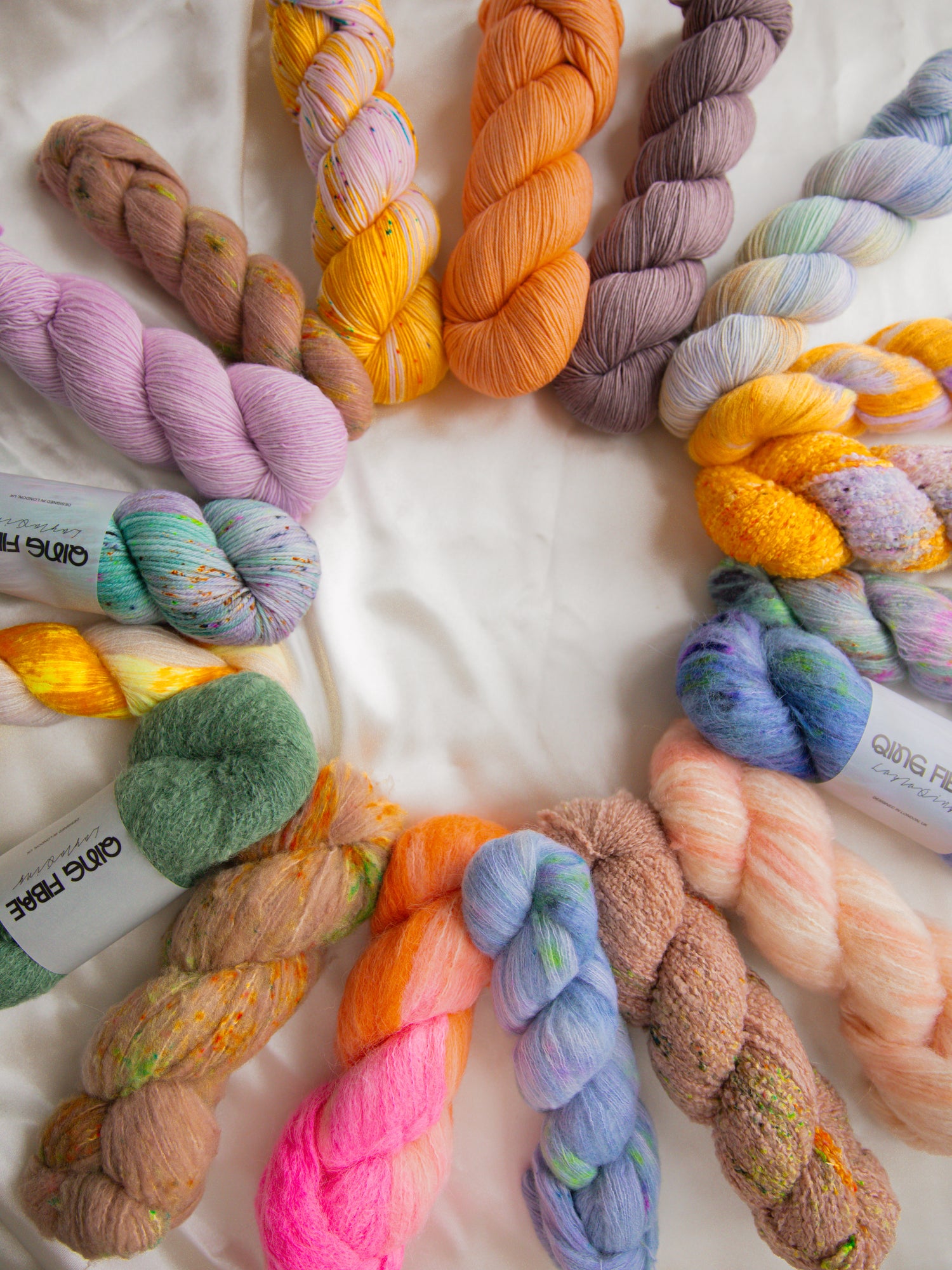 Colorful yarn skeins arranged in a circular pattern on a white background, hand dyed yarn