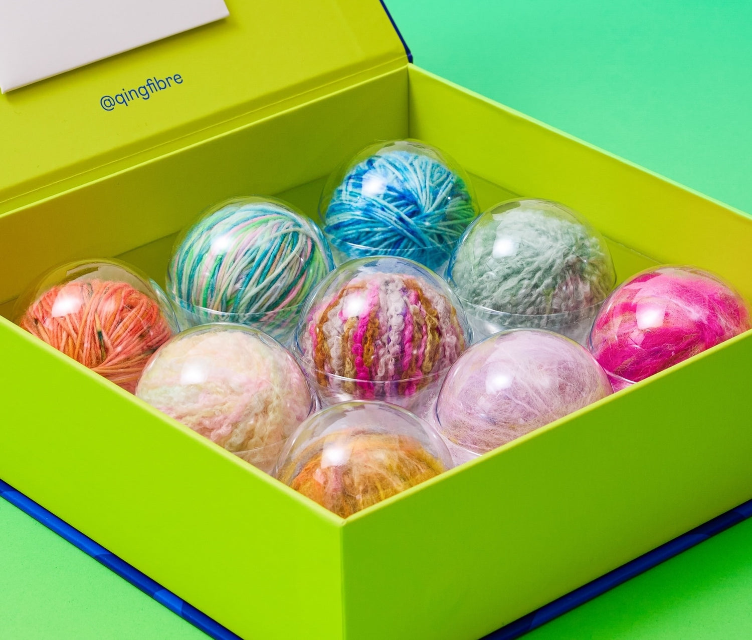 Close-up of hand-dyed yarn balls inside the Qing Fibre Taster Box, showing vibrant colour range