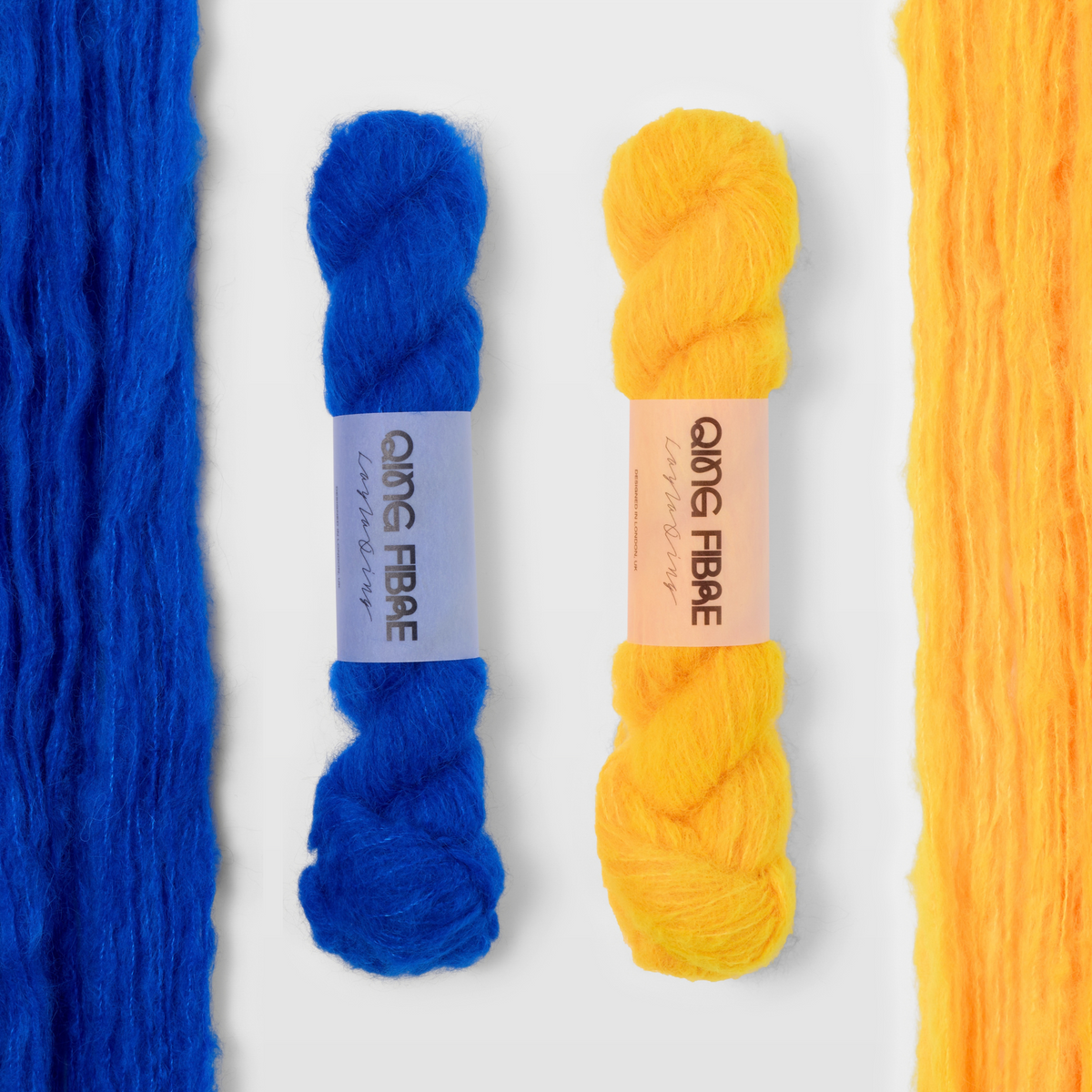 Hero blue and Cheese yellow Melted Baby Suri 25g yarn, with two twisted skeins between the open skeins on a grey background.