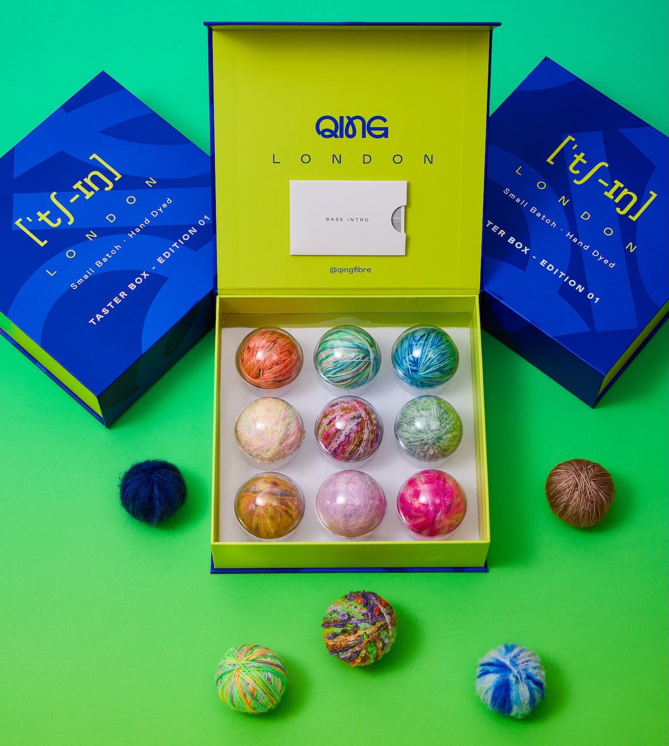 Qing Fibre Taster Box Edition 01 — open gift box displaying 9 hand-dyed mini yarn balls in vibrant colourways across Merino, Suri Alpaca and Boucle bases
