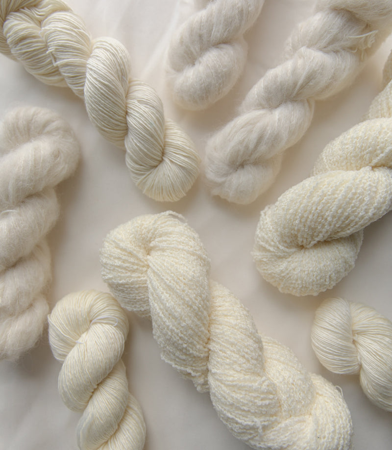 Undyed yarn skeins showing the natural texture of Merino, Suri Alpaca and Boucle bases before hand-dyeing